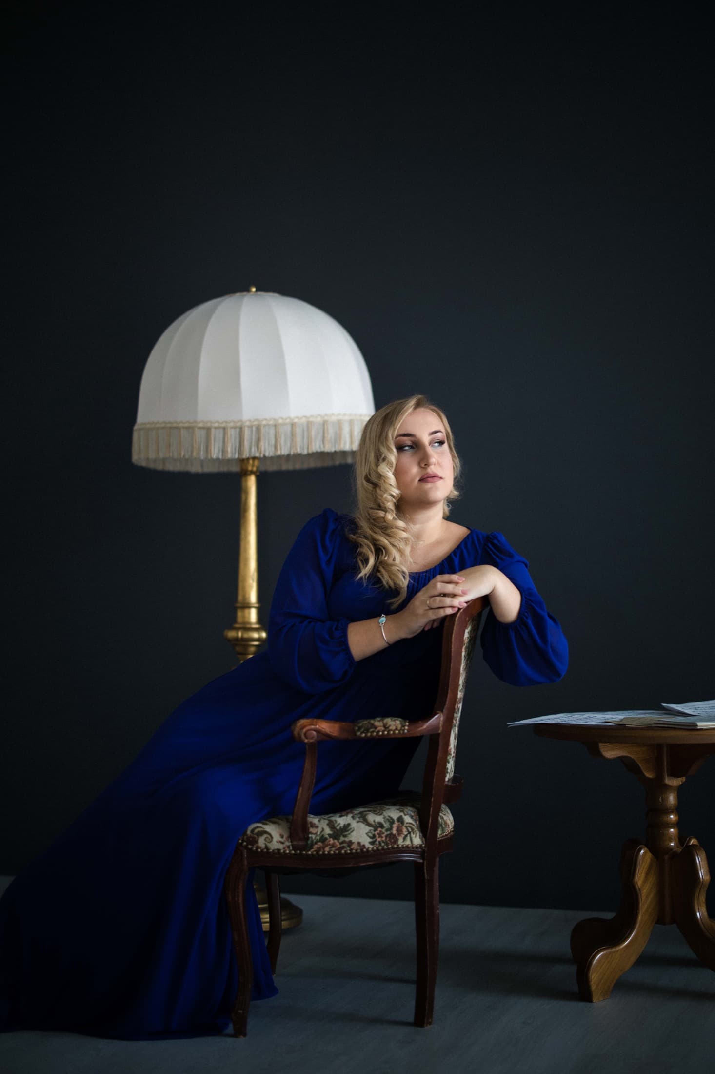 Jovana Filipović Ćalić seated in a royal-blue dress beside a lamp